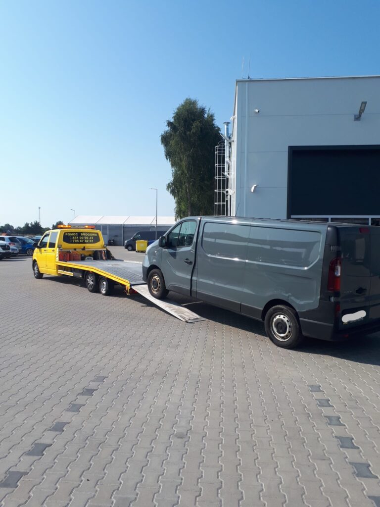 Laweta Polska przewożąca uszkodzony samochód na tle autostrady – bezpieczny i szybki transport pojazdów w Polsce.