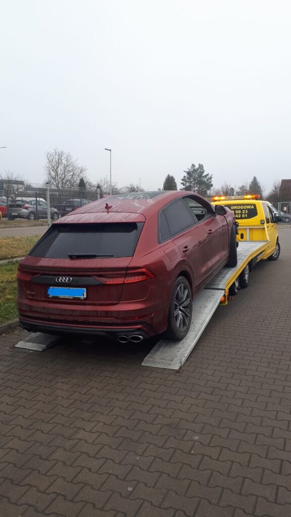Laweta Polska transportująca samochód osobowy po ośnieżonej drodze w zimowych warunkach