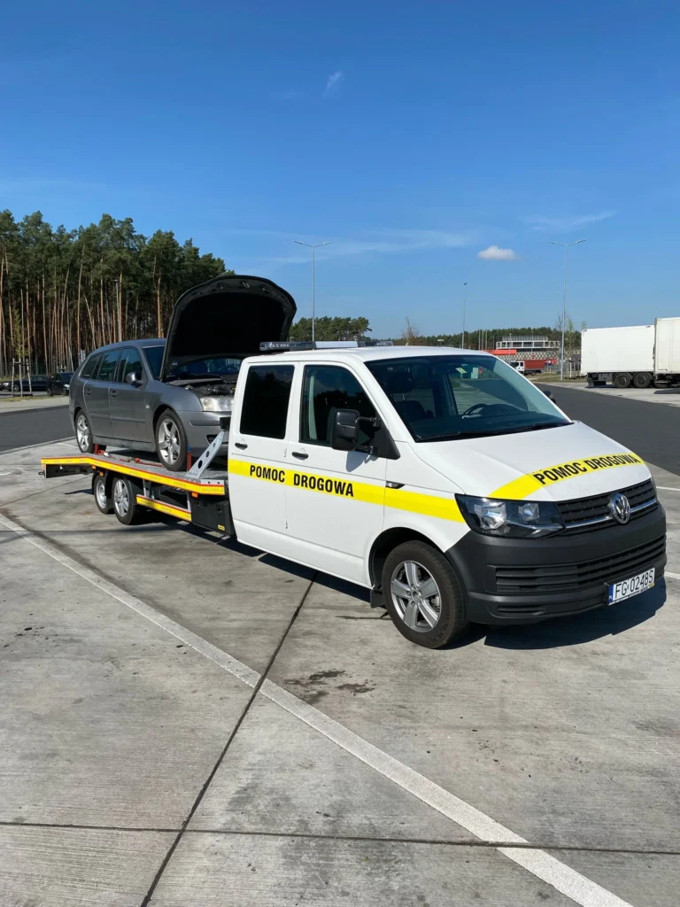 Laweta Polska transportująca uszkodzony samochód na tle drogi krajowej – szybka i profesjonalna pomoc na trasie
