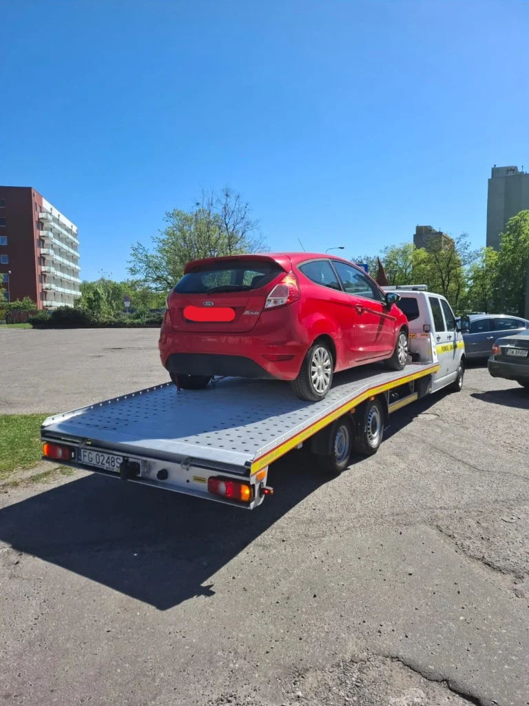 Laweta Polska transportująca samochód osobowy na tle polskiej drogi